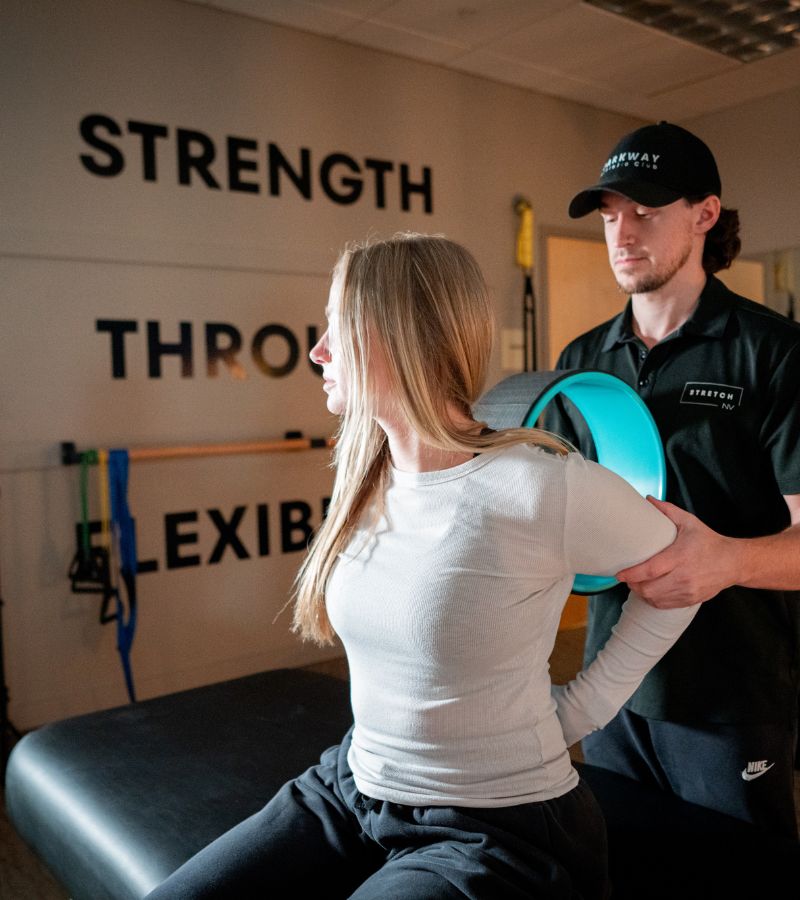 Trainer assisting a woman with shoulder mobility stretching at a Reno gym focused on strength, flexibility, and recovery.